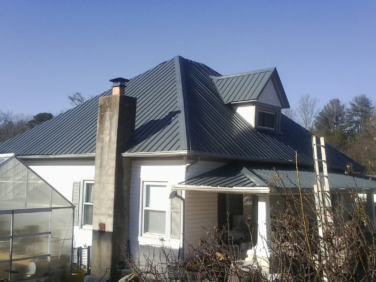 Dark blue standing seam metal roof on a white farmhouse with dormer — Slate & Tile Roof Repair by Roofing Brothers in Orting