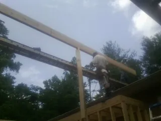 Carpenter setting a ridge beam over a new addition frame — Ice Dam Removal by Roofing Brothers in Orting