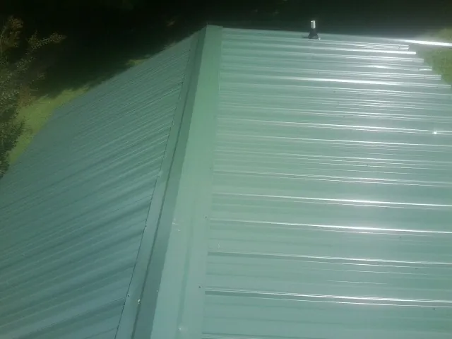 New green metal panels meeting at the ridge of a roof — Flat Roof Repair work by our crew in Orting