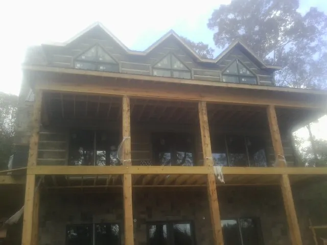 Dormers and porch framing on a large log home under construction — Roof Coating work by our crew in Orting