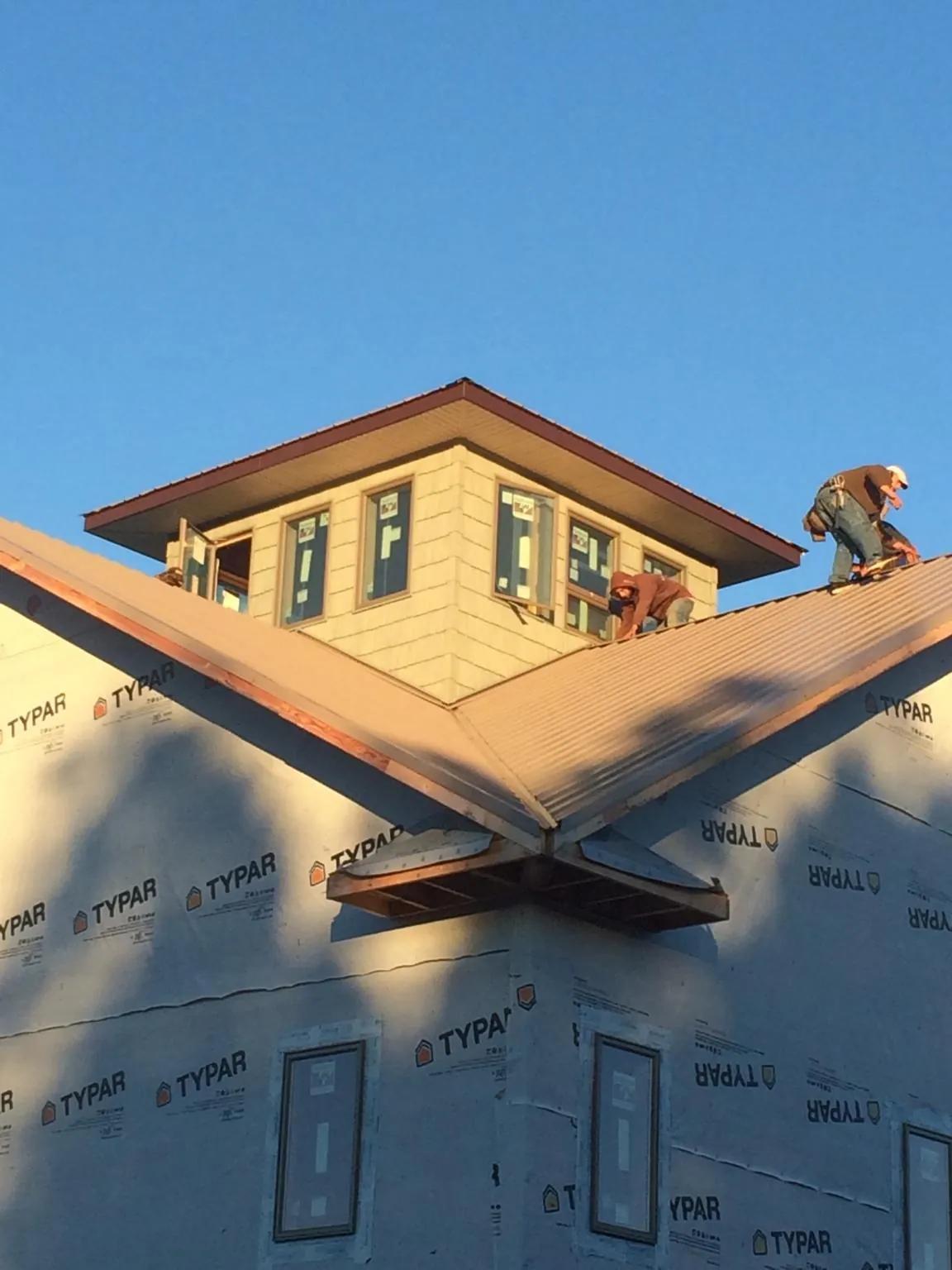 Roofers working around a rooftop cupola on a new metal roof at sunset — Roof Waterproofing in Orting by Roofing Brothers
